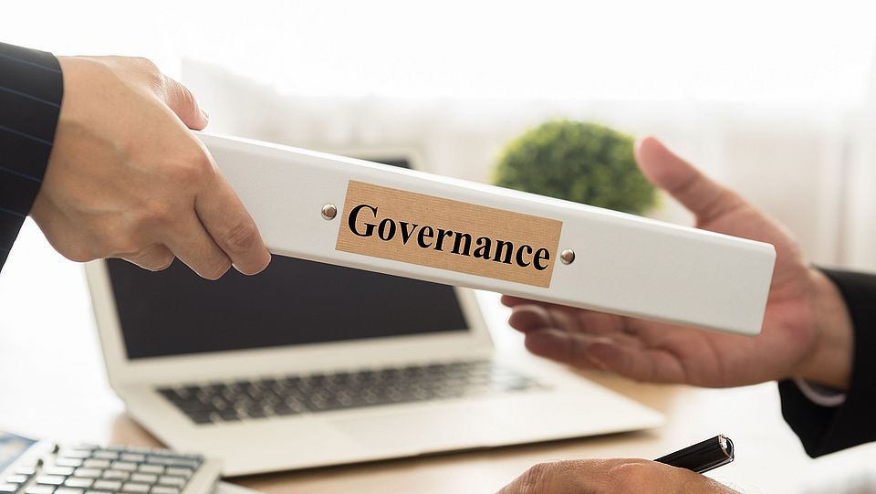 Ein Ordner mit dem Titel "Governance" wird überreicht