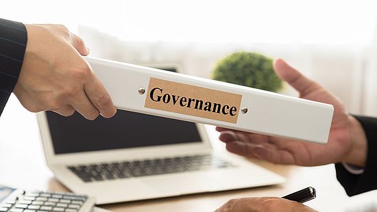 A folder with the title "Governance" is handed over